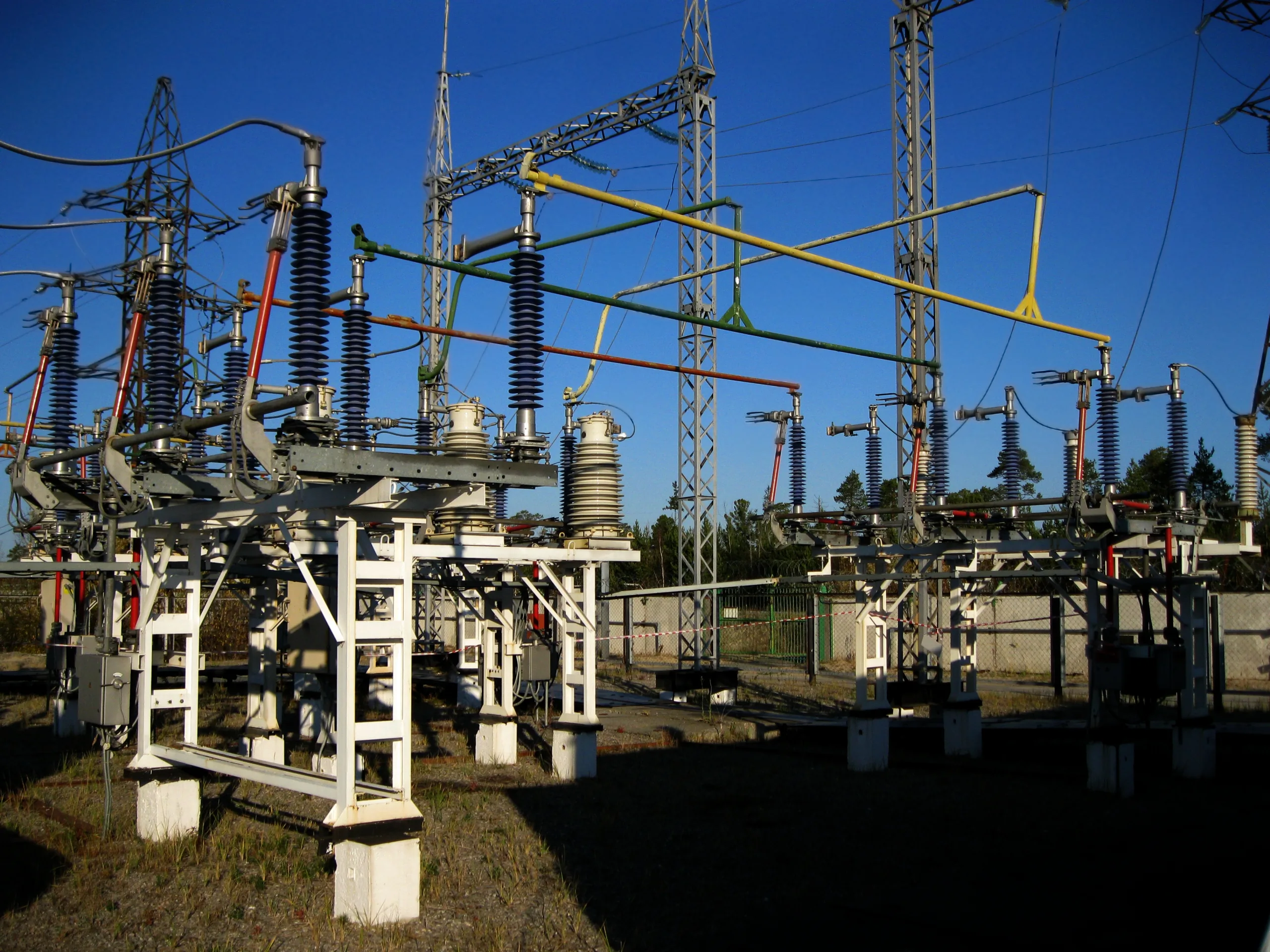 Equipos de una subestación eléctrica con aisladores e interruptores de alta tensión al atardecer